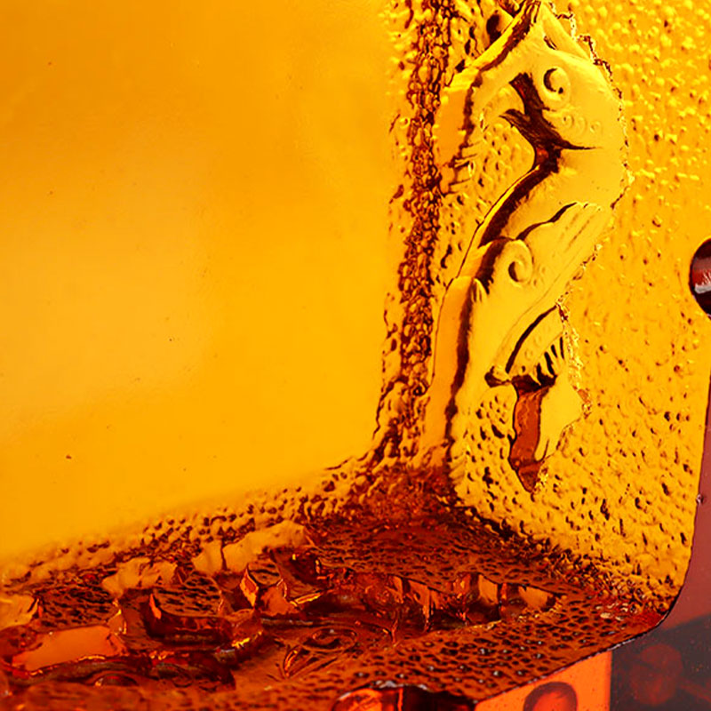 Röd askkopp i glas med utsökt präglade djurmönster