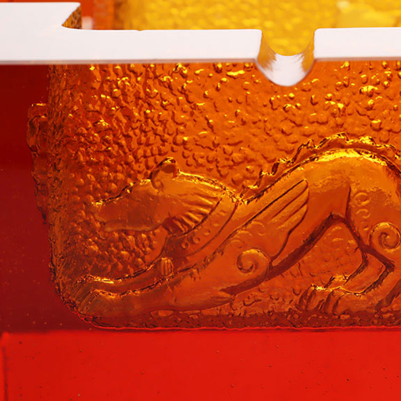 Röd askkopp i glas med utsökt präglade djurmönster